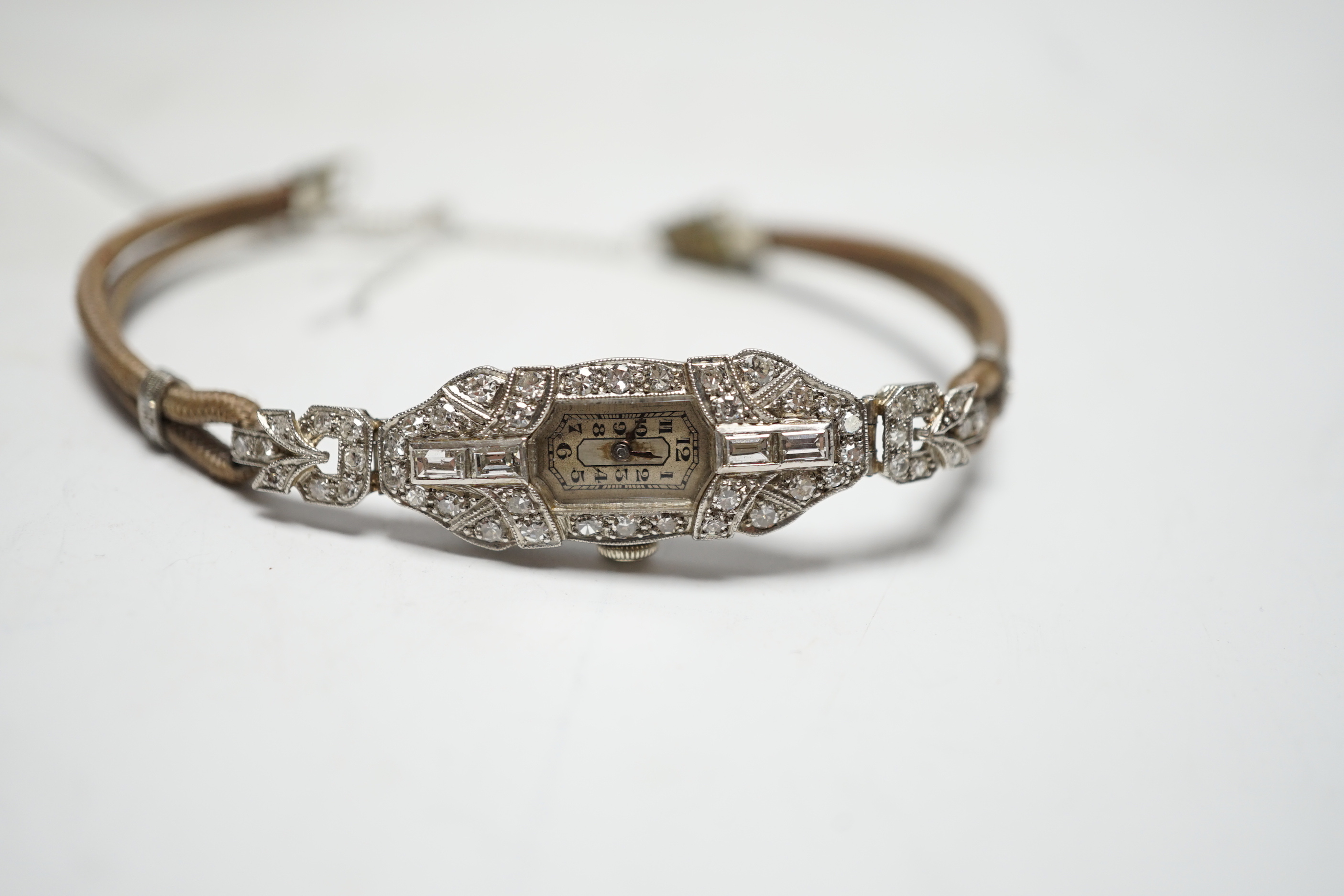 A lady's 1940's/1950's white metal (engraved platinum) and diamond cluster set manual wind cocktail watch, on a twin fabric strap.